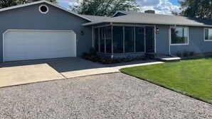 Einbungalow mit Garage, überdachter Veranda und gepflegtem Rasen.