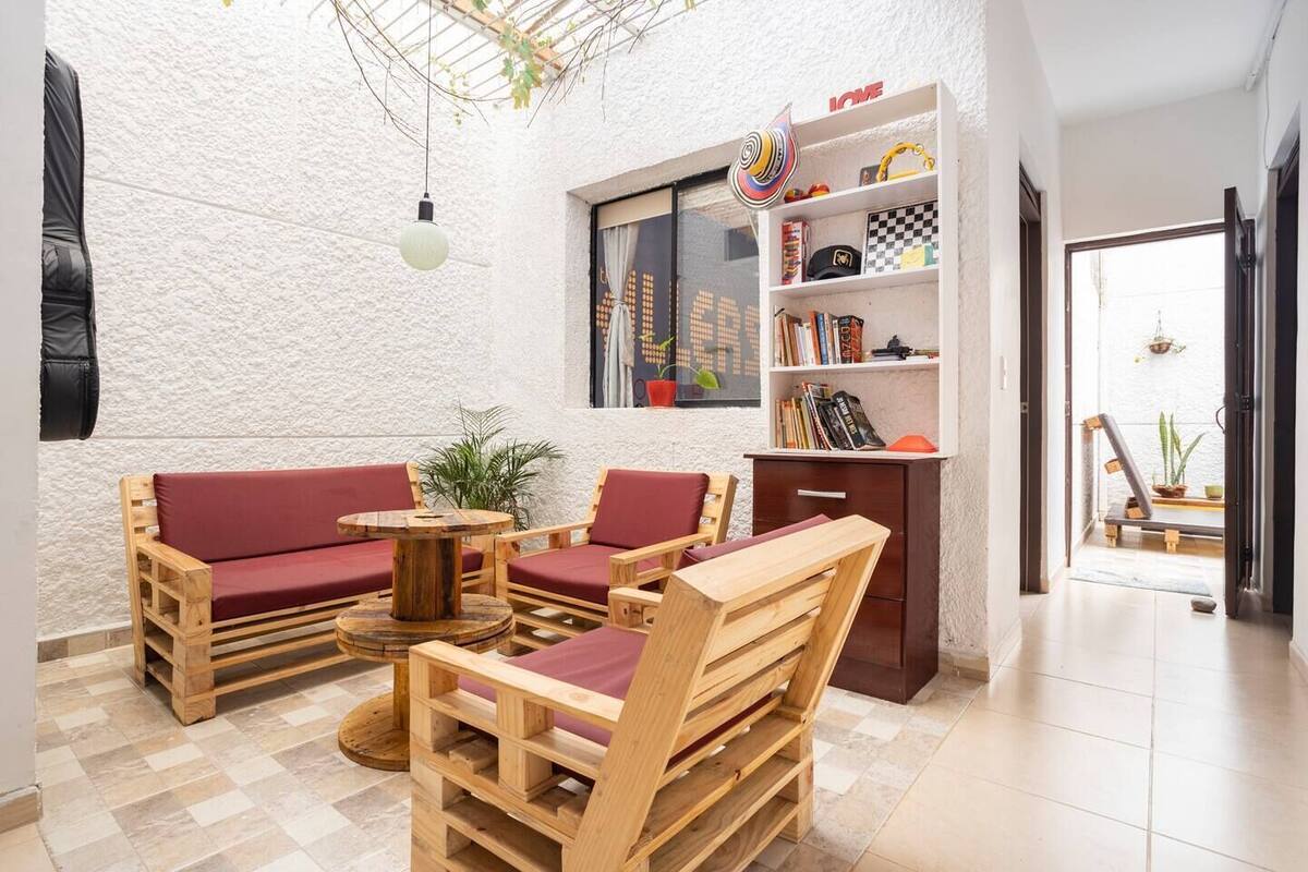 Um quarto acolhedor com um conjunto de sofá de madeira, uma mesa redonda pequena e uma estante com diversos objetos.