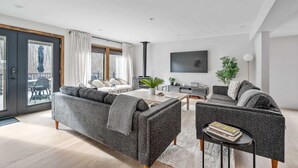 Ein modernes Wohnzimmer mit grauem Sofa, einem Couchtisch und einem an der Wand montierten Fernseher.