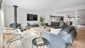 Ein modernes Wohnzimmer mit Kamin, einer Couch, einem Couchtisch und einem Fernseher.