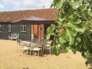A patio area with a table and chairs, a bench, and a large umbrella. - Perfect tranquillity. (Weston Longville)