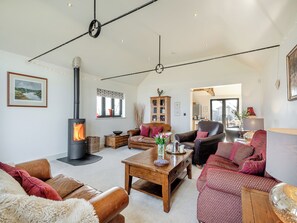 A cozy living room with a fireplace, leather sofas, a wooden coffee table, and a view into the kitchen. - Perfect tranquillity. (Weston Longville)