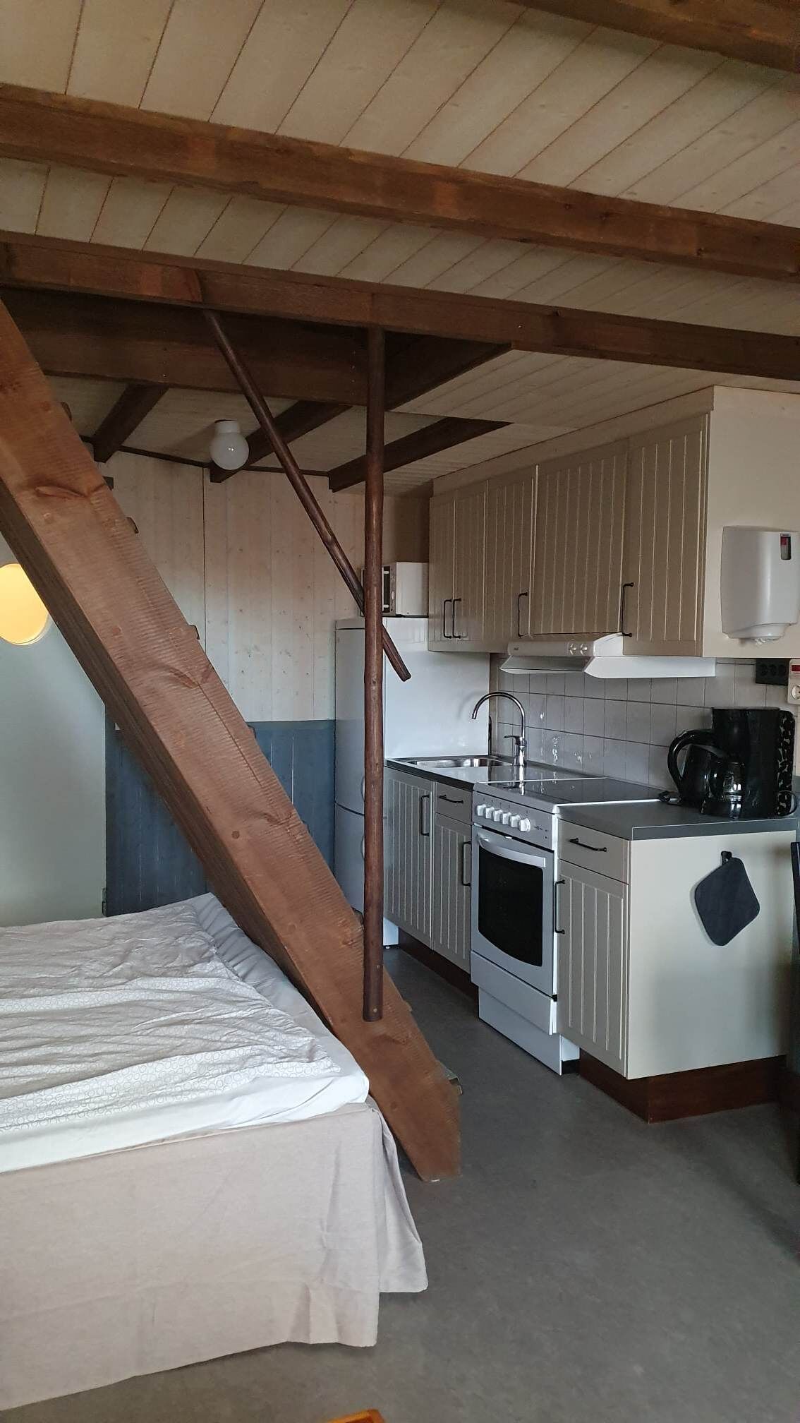 A compact kitchen with wooden beams, a stove, and a sink.