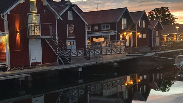 A waterfront property with a dock extending into calm water, reflecting the buildings. - Epokgården (Öregrund)