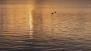 A calm sea at sunset with two boats in the distance.