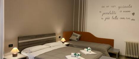 Habitación de hotel con cama, mesitas de noche, lámpara, aire acondicionado instalado en la pared y radiador. En la pared, una cita motivacional.