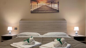 A hotel room with a large bed, two nightstands, a painting of a pier, and towels on the bed. - Villa Anna (Brindisi)