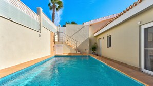 A swimming pool with a tiled edge, a staircase leading to a door, and a palm tree in the background. - Fabulous villa with private pool in the south of Tenerife! Amazing views! (Costa Adeje)