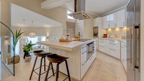 A modern kitchen with a central island, stainless steel appliances, and a large window providing natural light. - Fabulous villa with private pool in the south of Tenerife! Amazing views! (Costa Adeje)