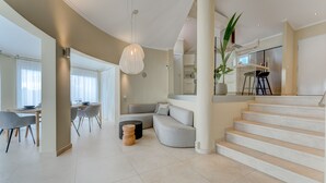 A spacious living area with a dining table, a sofa, and a staircase leading to an upper floor. - Fabulous villa with private pool in the south of Tenerife! Amazing views! (Costa Adeje)