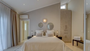 A spacious bedroom with a large bed, bedside tables, a wardrobe, and a bench with towels. - Fabulous villa with private pool in the south of Tenerife! Amazing views! (Costa Adeje)