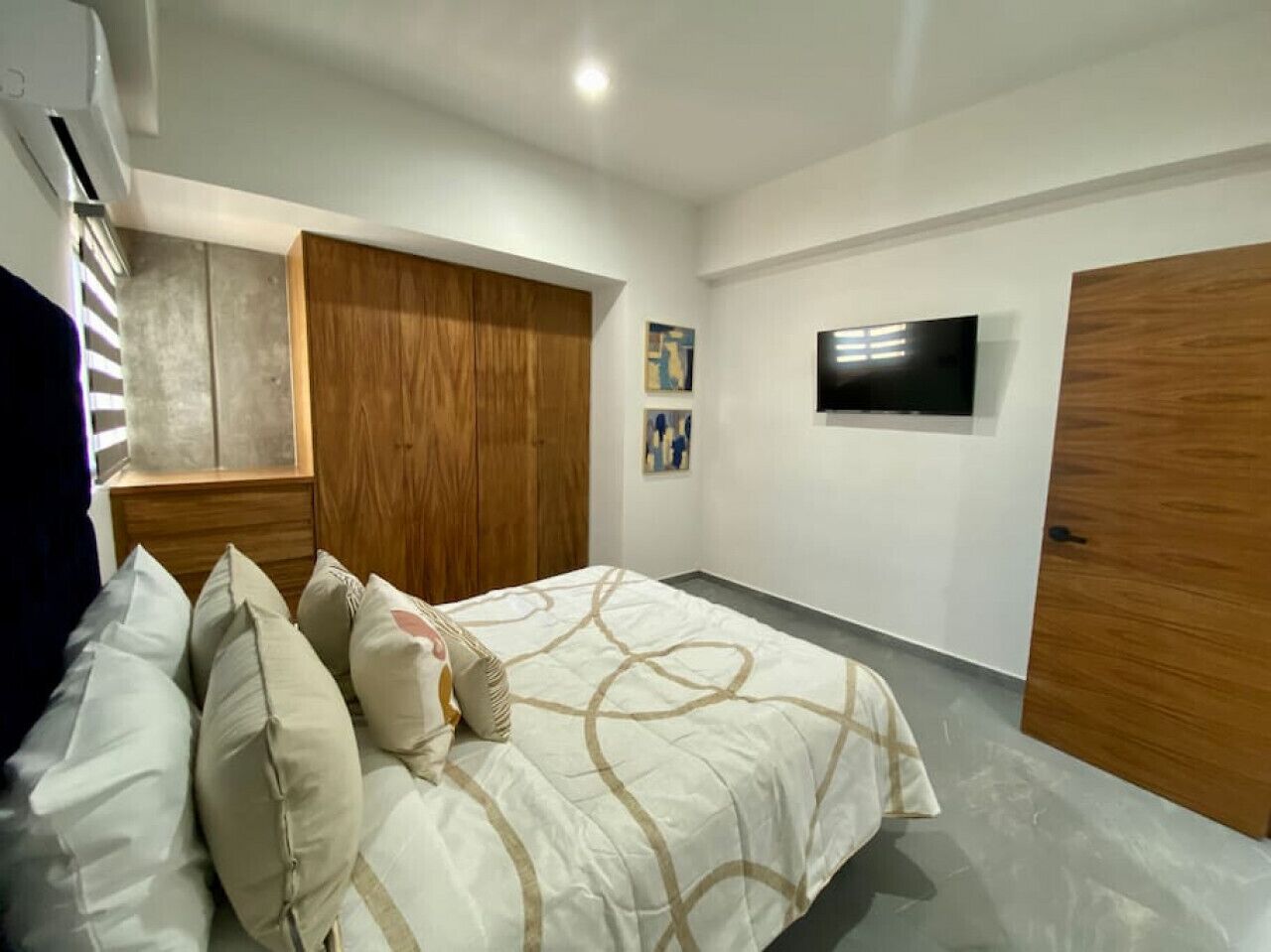 A bedroom with a bed, a wardrobe, a television, and a door.