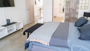Ein modernes Schlafzimmer mit Bett, Fernseher, Schreibtisch und Blick ins Freie.