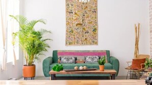Ein geräumiges Wohnzimmer mit Holzboden, einem grünen Sofa, einem Couchtisch und einem großen Wandteppich.