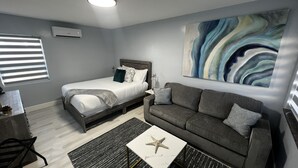 A modern bedroom with a bed, a gray sofa, a coffee table with a starfish, and a painting on the wall.