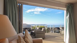 A room with a sofa and a chair facing a large sliding glass door.