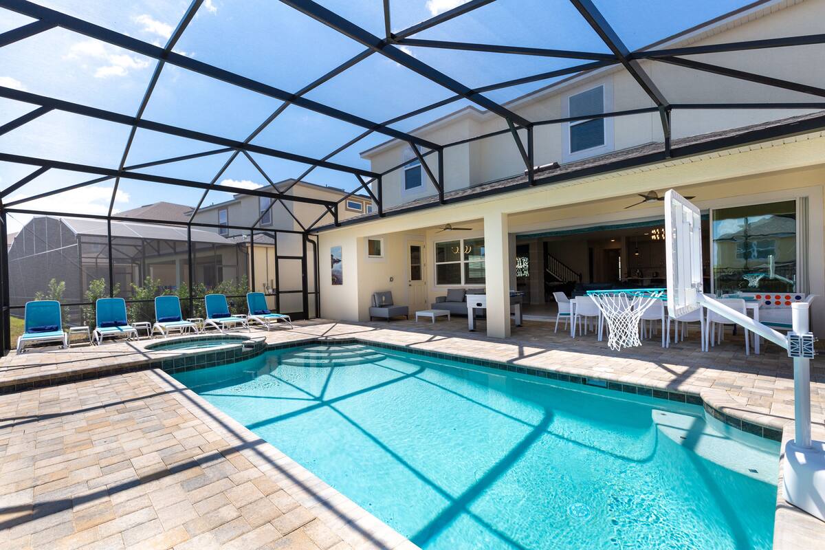 A pool area with a clear blue pool, lounge chairs, and a covered seating area.