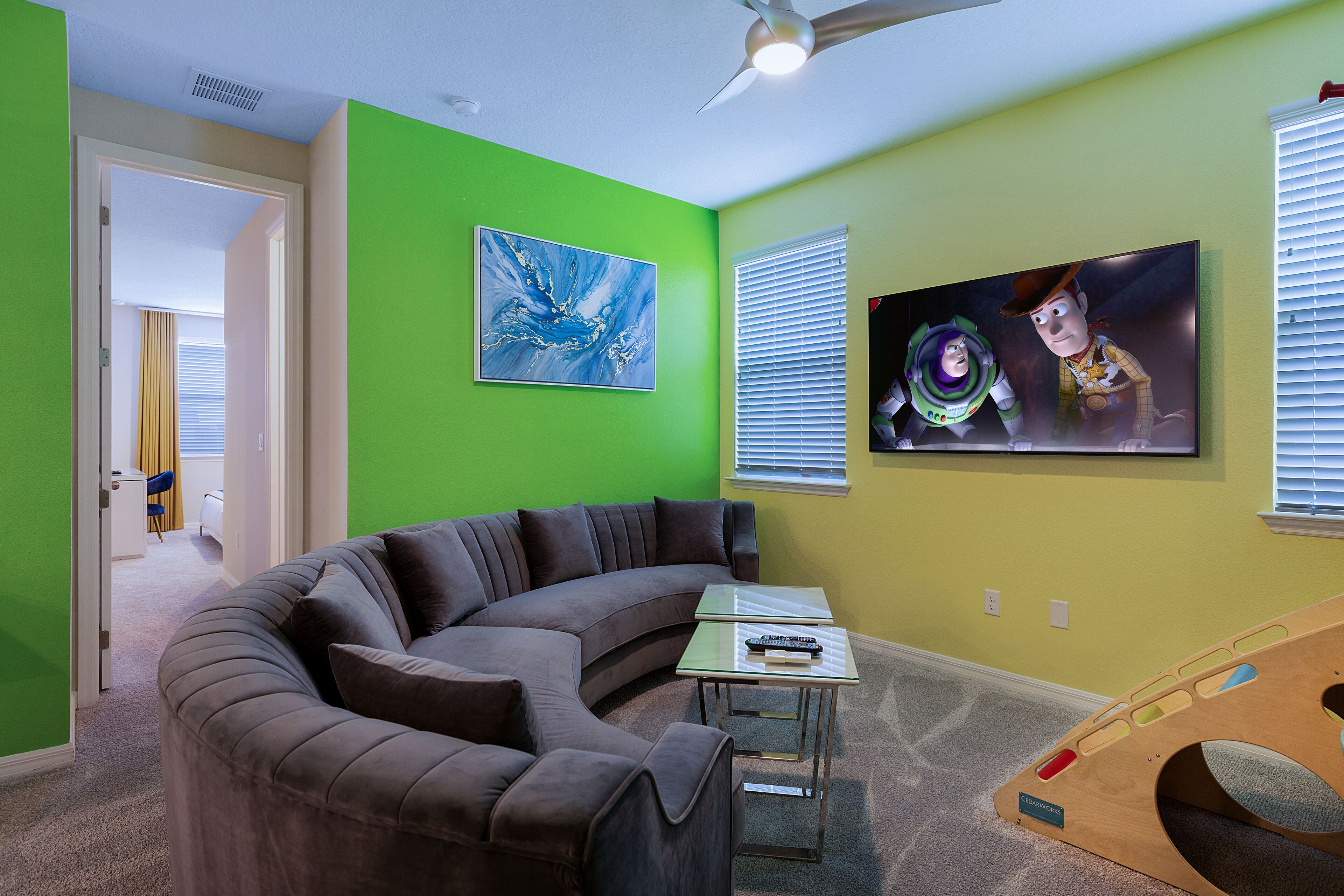 Una sala de estar con un sofá modular curvo, una mesa de centro de vidrio y dos cuadros colgados en la pared.