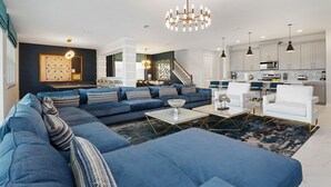 A modern living room with a sectional sofa, a coffee table, and a staircase leading to an upper level. - Villatel at Solara Resort - 8BRs (Kissimmee)