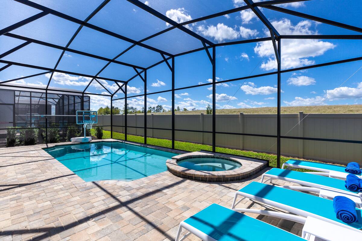 A backyard with a swimming pool, hot tub, and lounge chairs.
