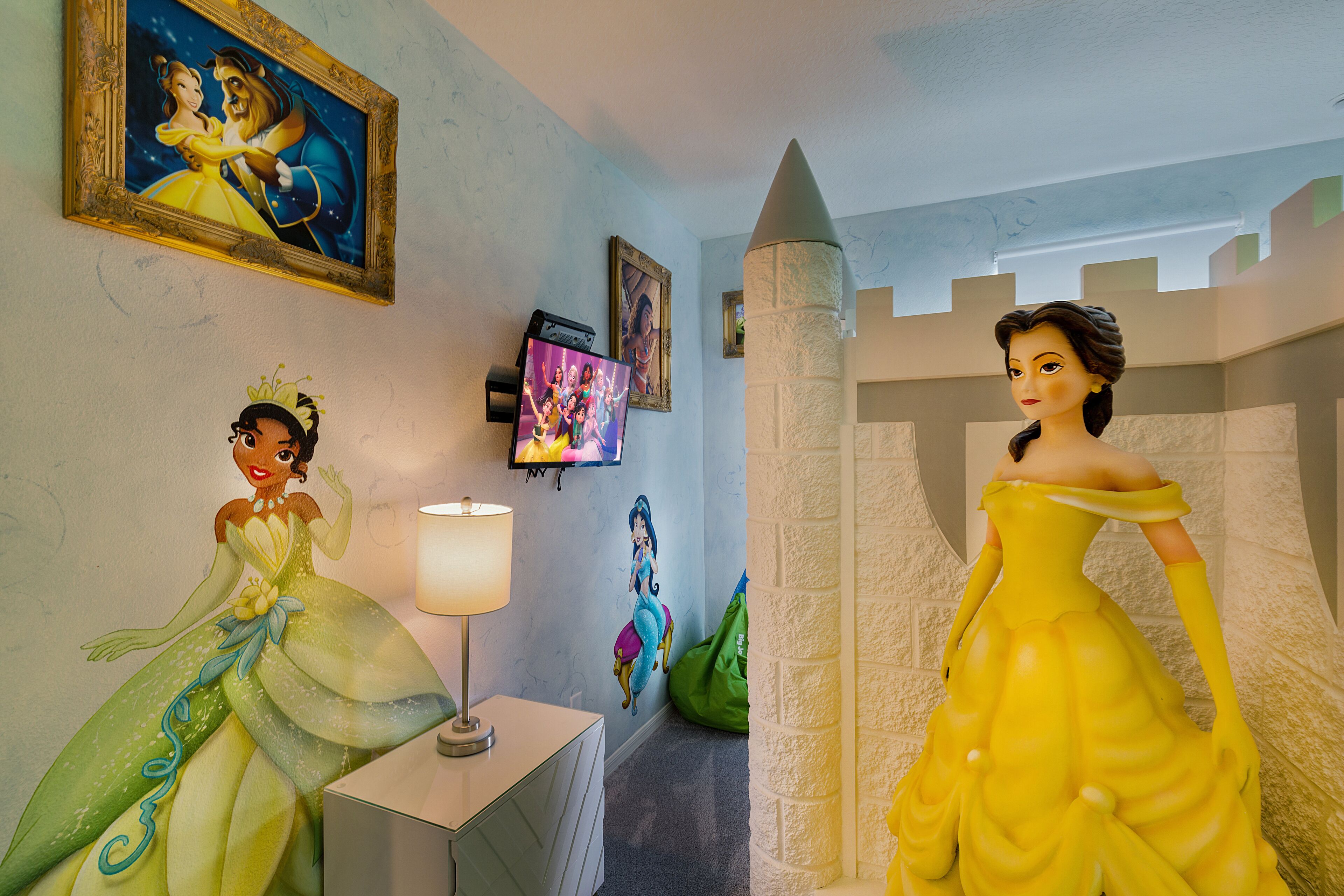 Une pièce avec un mur décoré sur le thème d’un château, une télévision et une lampe.