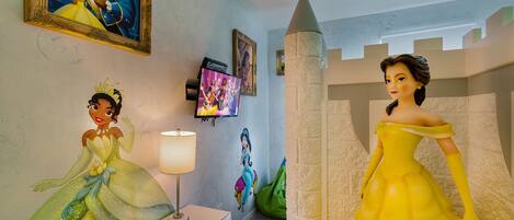 Une pièce avec un mur décoré sur le thème d’un château, une télévision et une lampe.
