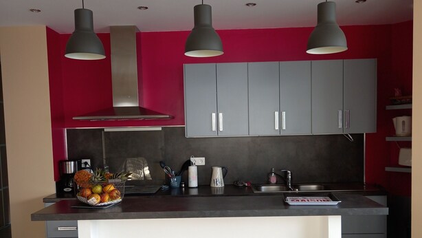 Una cocina moderna con gabinetes grises, una isla central con taburetes e iluminación colgante.