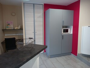 Una cocina con un armario gris, un microondas y un refrigerador blanco.