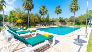 A poolside area with lounge chairs and a table, surrounded by palm trees and greenery. - GALLINA Finca with pool for 8 people in Alcudia (Alcúdia)