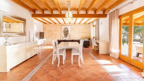 A spacious dining area with a wooden ceiling, a central table with chairs, and a stone wall with a painting. - GALLINA Finca with pool for 8 people in Alcudia (Alcúdia)