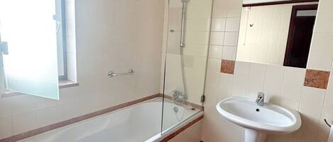 A bathroom with a bathtub, a shower, and a sink.