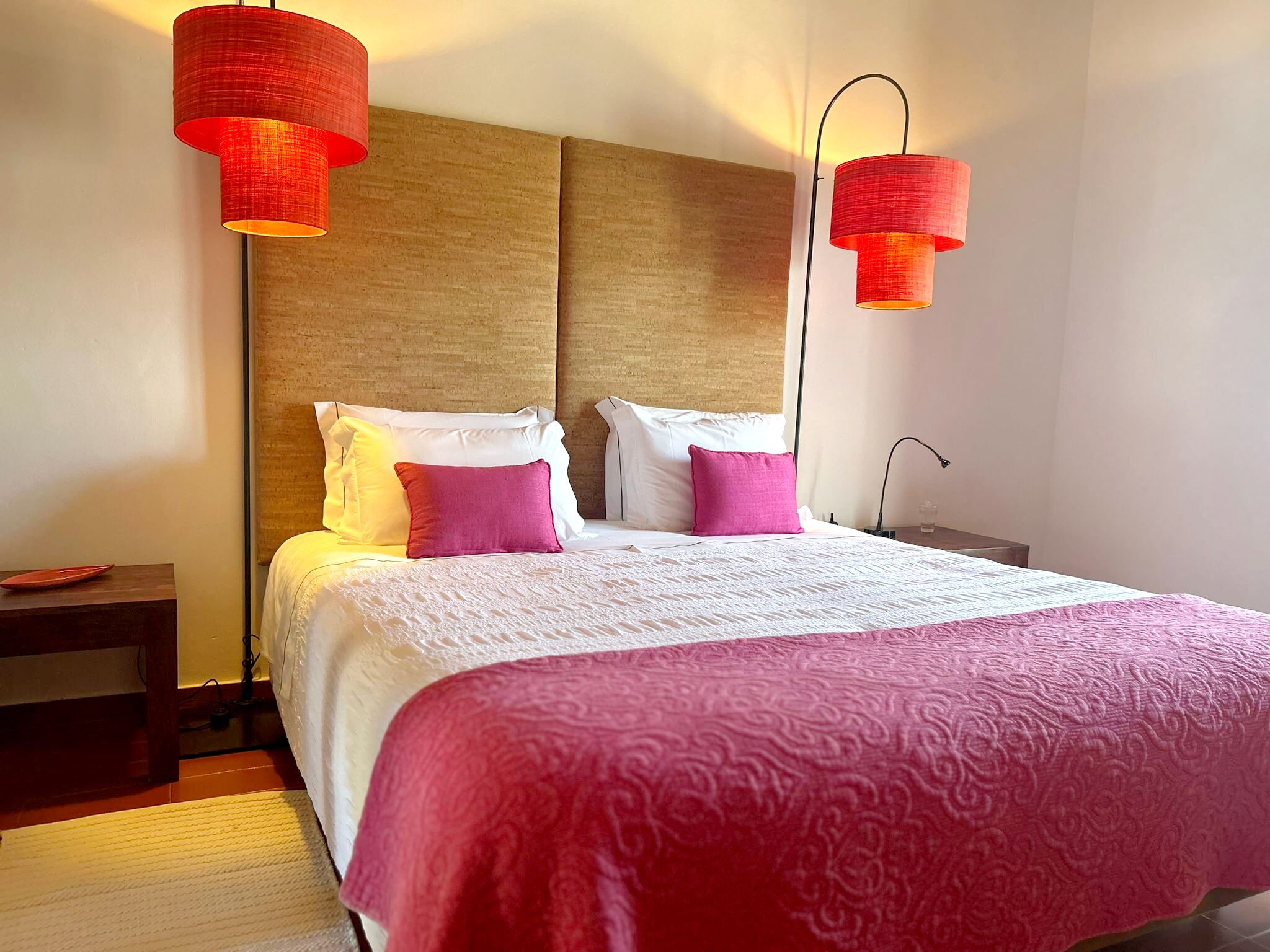 Una habitación de hotel con una cama grande, dos lámparas de noche y una mesita de noche.
