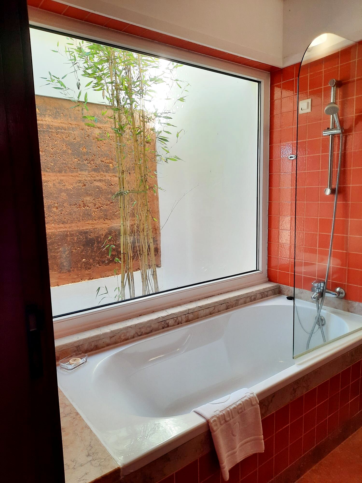 A bathroom with a large window, a bathtub, and a shower.