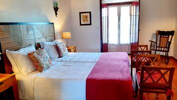 Un letto matrimoniale con testiera, comodini, una lampada, un quadro incorniciato e una sedia.