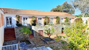 Un patio con escalones de piedra, un pequeño jardín y un edificio con tejado de tejas.