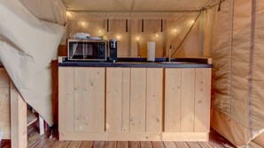 Cozinha compacta com micro-ondas, cafeteira e luzinhas.