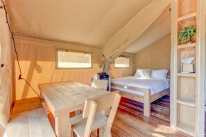 Alojamiento en carpa con cama, una mesa y una silla.