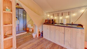 A compact, modern bathroom with a wooden vanity, a shower area, and a small sink.