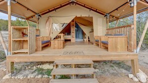 A wooden tent with a covered porch, benches, and a 'Hello' sign on the floor.