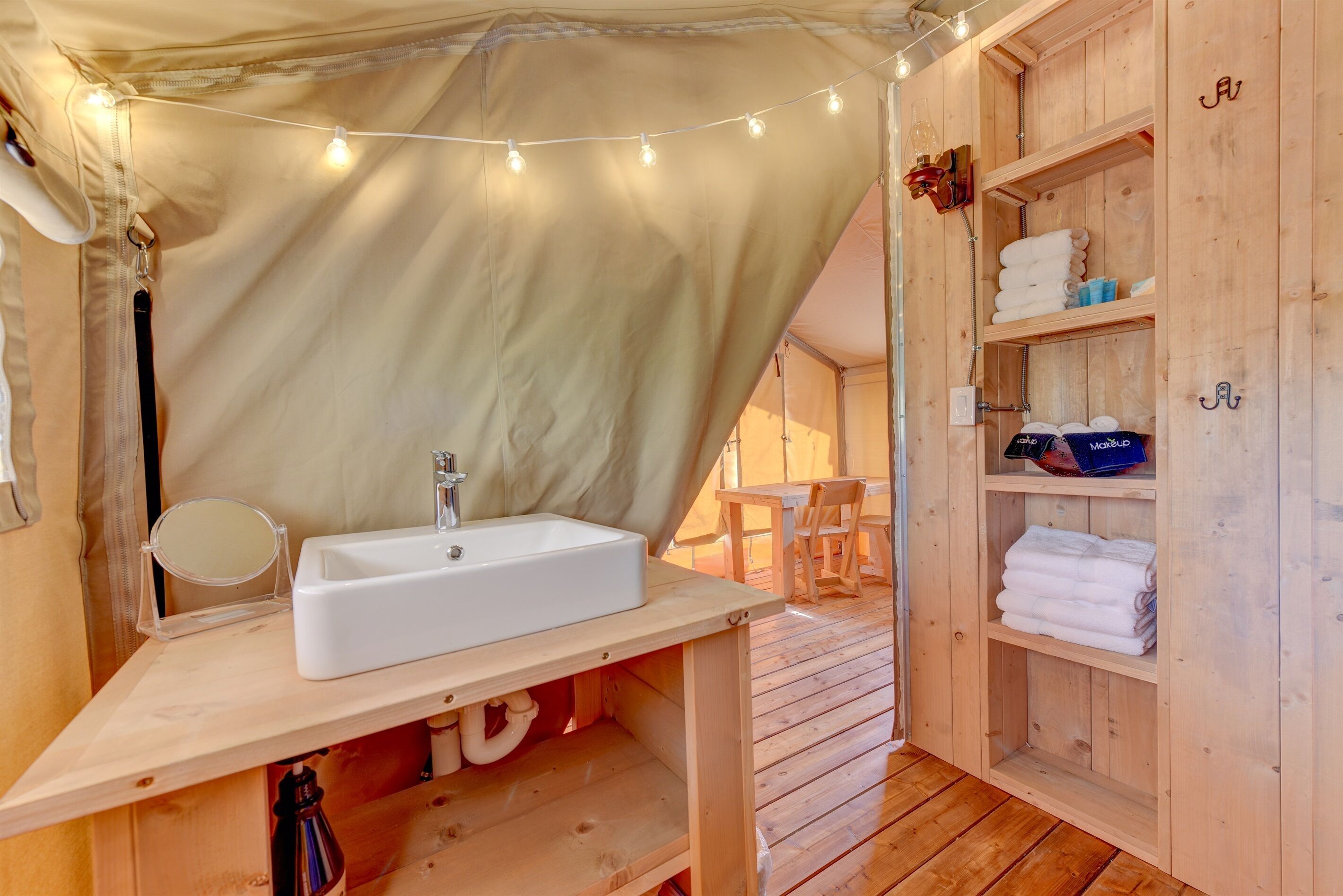A wooden cabin interior with a sink, mirror, and shelves for towels.