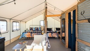 Un hébergement sous tente comprenant deux lits, une table et une chaise.