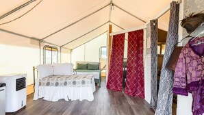A tented room with a bed, a table, and a heater.