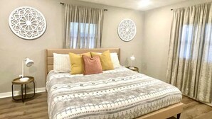 Une chambre à coucher avec un grand lit, deux tables de chevet et des œuvres d’art décoratives au mur.