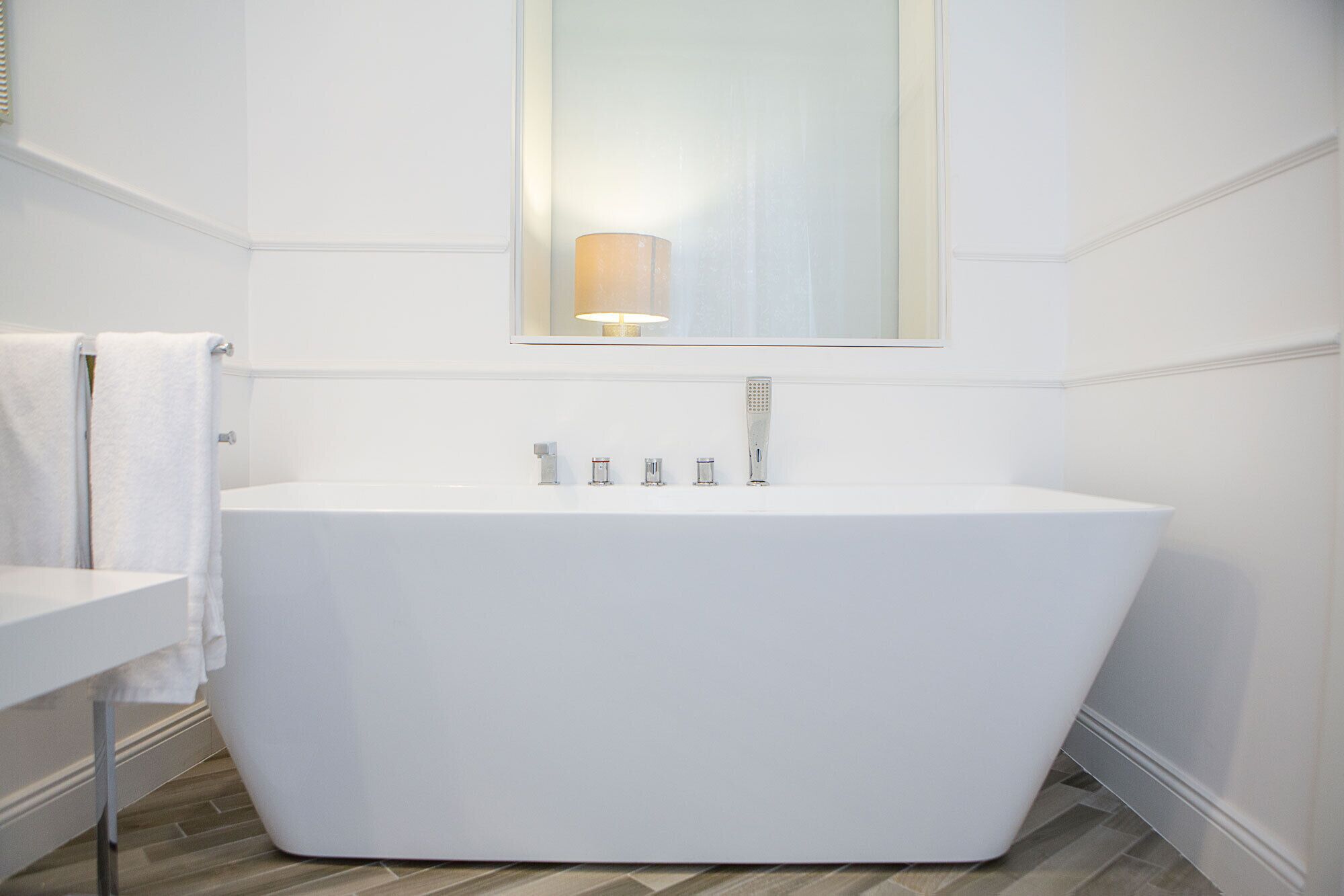 A modern bathroom with a freestanding bathtub, a white sink, and a wall-mounted mirror.