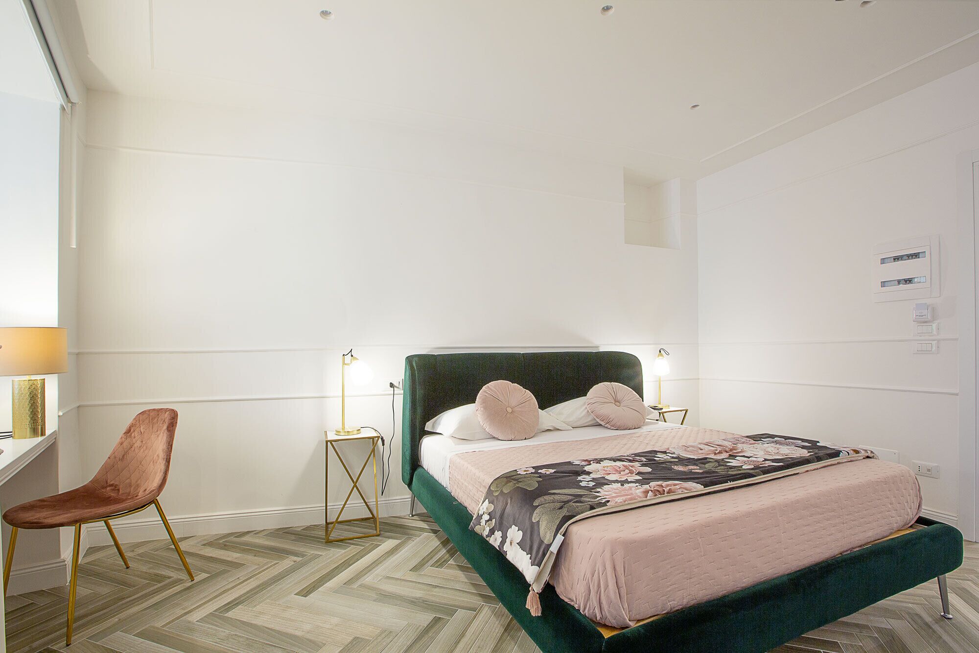 A bedroom with a bed, a chair, a nightstand, and a lamp.