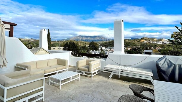 Terraza en la azotea con mobiliario exterior, una pérgola y vistas al paisaje.
