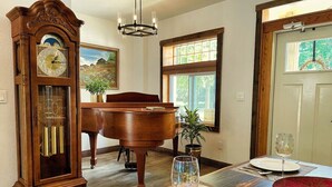 Un comedor con una mesa de madera, un reloj de pie, un piano y un juego de comedor.