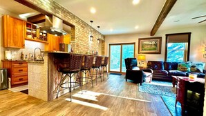 Una cocina amplia con una pared de ladrillo decorativa, armarios de madera y una zona de bar con taburetes.