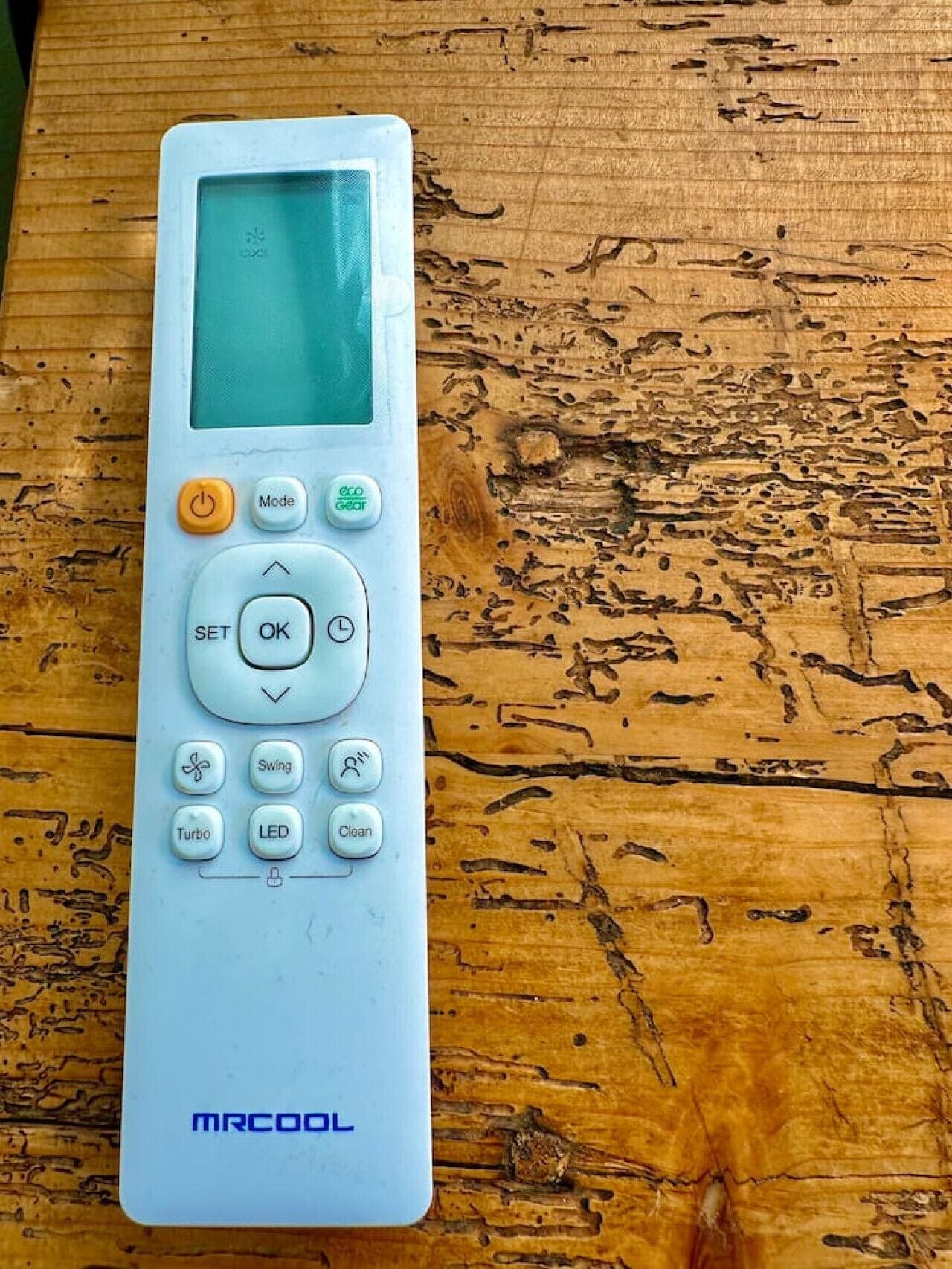 A white MRCOOL remote control on a wooden surface.