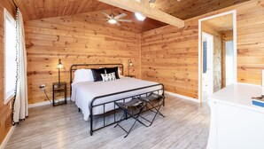 A wooden-paneled bedroom with a bed, bedside lamps, and a ceiling fan. - Island Cottage w/ Pool Table & Walking distance to Cranberry!  (Huntsville)
